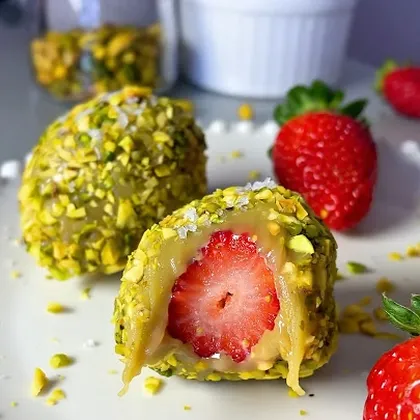 Morango cravejado de pistache partido ao meio, com crosta de pistache picado e creme escorrendo